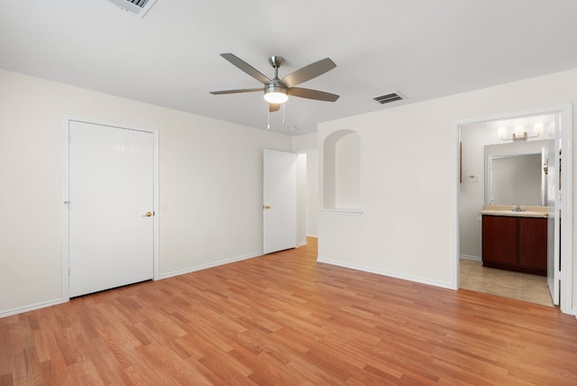 unfurnished bedroom featuring connected bathroom, ceiling fan, sink, and light wood-type flooring