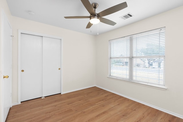 unfurnished bedroom featuring ceiling fan, light hardwood / wood-style floors, and a closet