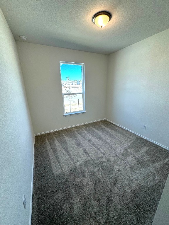 unfurnished room with carpet flooring, a textured ceiling, and baseboards