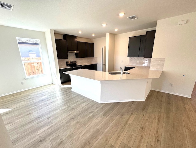 kitchen featuring a peninsula, black / electric stove, visible vents, and light countertops