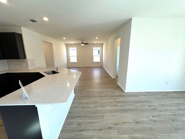 kitchen featuring open floor plan, dark cabinetry, a sink, and visible vents