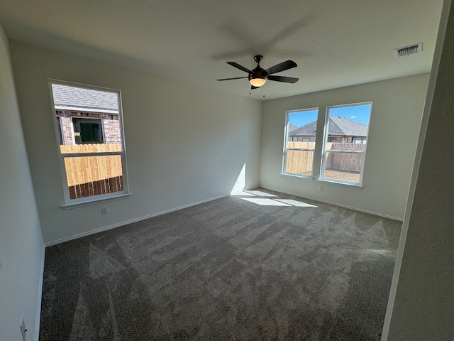 empty room with baseboards, visible vents, ceiling fan, and carpet flooring