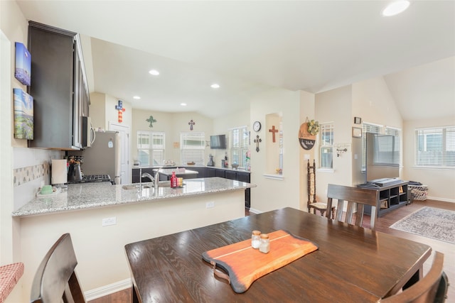 dining space with lofted ceiling, sink, and hardwood / wood-style flooring