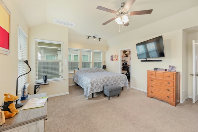 bedroom with ceiling fan, light colored carpet, vaulted ceiling, a spacious closet, and a closet