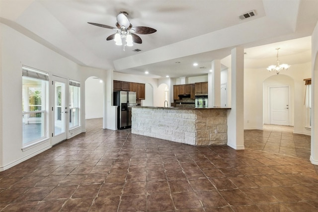 kitchen with kitchen peninsula, french doors, ceiling fan with notable chandelier, stainless steel appliances, and a tray ceiling