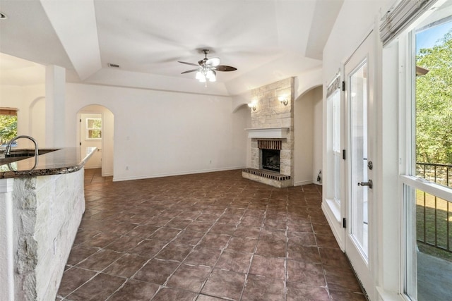 unfurnished living room featuring a tray ceiling, ceiling fan, and a fireplace