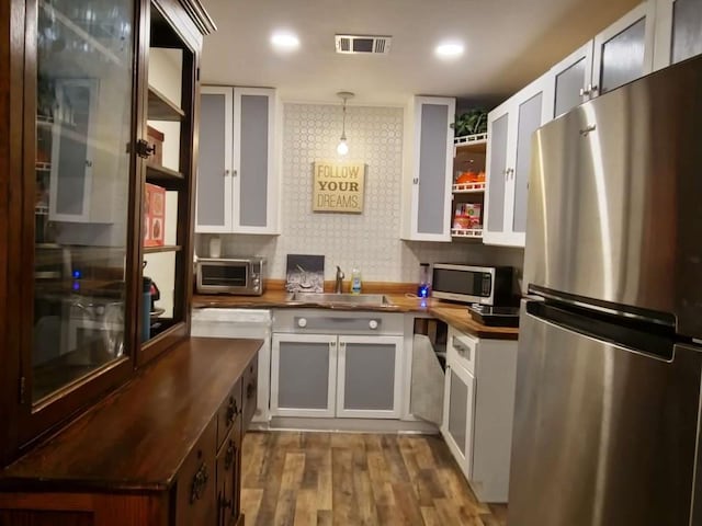 kitchen featuring decorative backsplash, appliances with stainless steel finishes, decorative light fixtures, butcher block countertops, and dark hardwood / wood-style floors