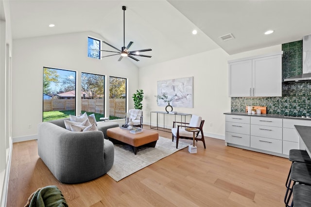 living room featuring high vaulted ceiling, ceiling fan, and light wood-type flooring