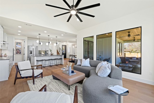 living room featuring vaulted ceiling, light hardwood / wood-style floors, and ceiling fan