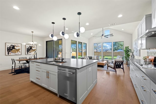 kitchen featuring wall chimney exhaust hood, stovetop, sink, pendant lighting, and white cabinets