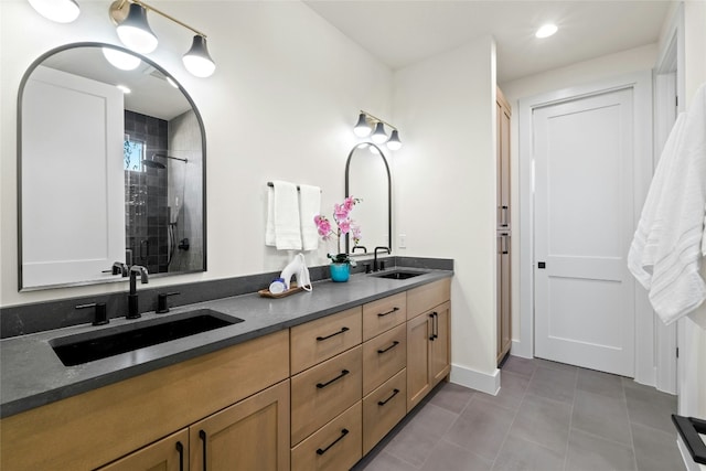 bathroom featuring tile patterned flooring, vanity, and a tile shower