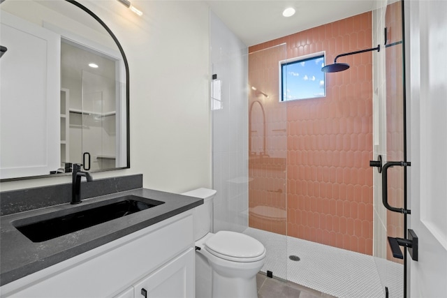 bathroom featuring a shower with door, vanity, and toilet