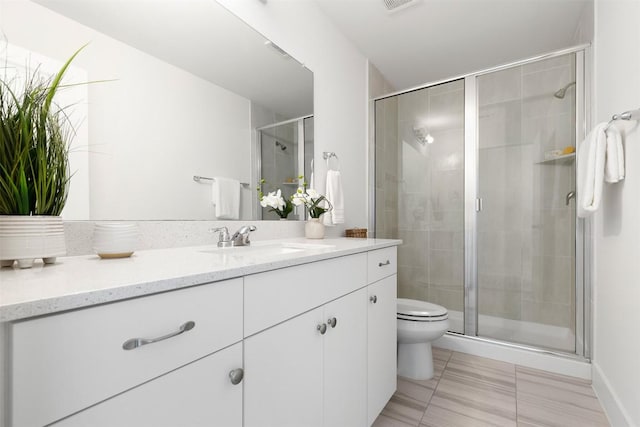 bathroom with tile patterned floors, vanity, toilet, and a shower with door