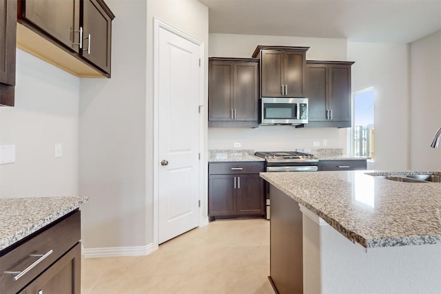 kitchen with dark brown cabinetry, light stone countertops, sink, and stainless steel appliances