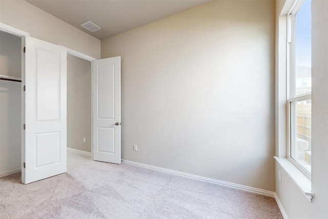 unfurnished bedroom featuring light carpet and a closet