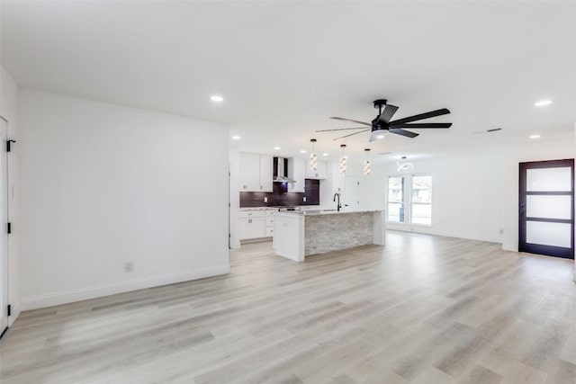 unfurnished living room with ceiling fan and light hardwood / wood-style flooring