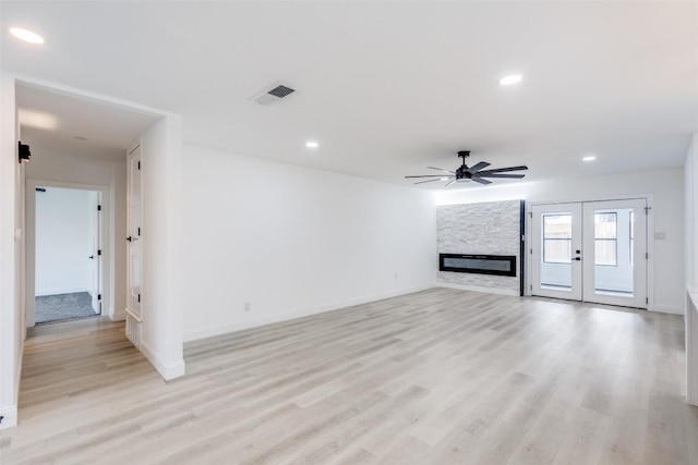 unfurnished living room with ceiling fan, french doors, a fireplace, and light hardwood / wood-style flooring