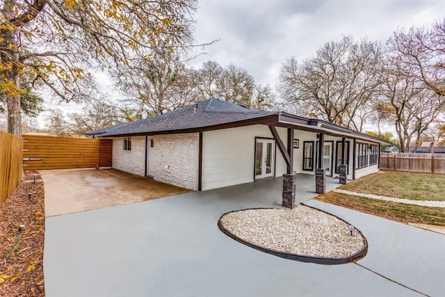 view of side of property featuring a lawn, a patio area, and french doors