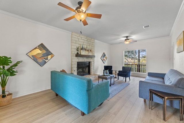 living room with ceiling fan, a stone fireplace, light wood-type flooring, and crown molding