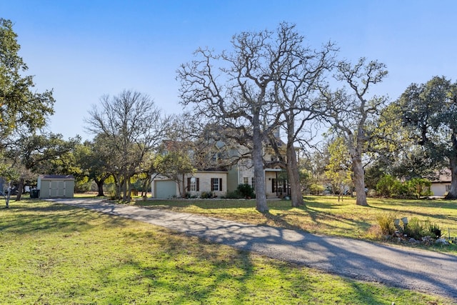 view of front of house featuring a storage shed, a front lawn, and a garage