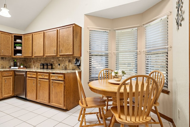 kitchen featuring backsplash, light stone countertops, vaulted ceiling, and decorative light fixtures