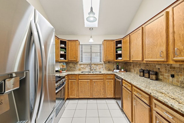 kitchen with appliances with stainless steel finishes, light stone counters, sink, light tile patterned floors, and pendant lighting