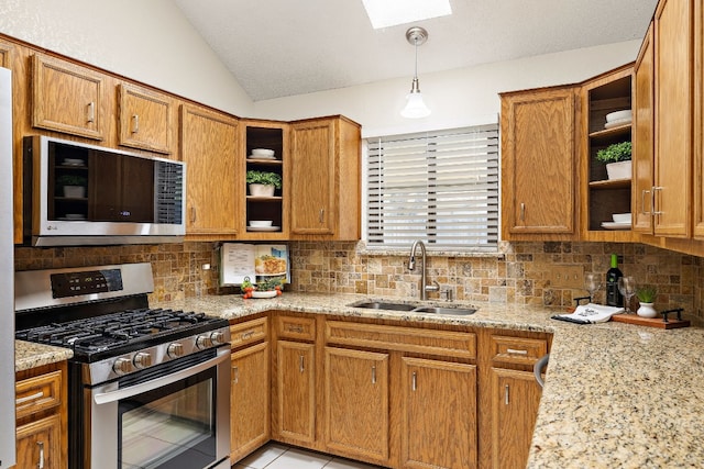 kitchen with light stone countertops, sink, decorative light fixtures, and appliances with stainless steel finishes