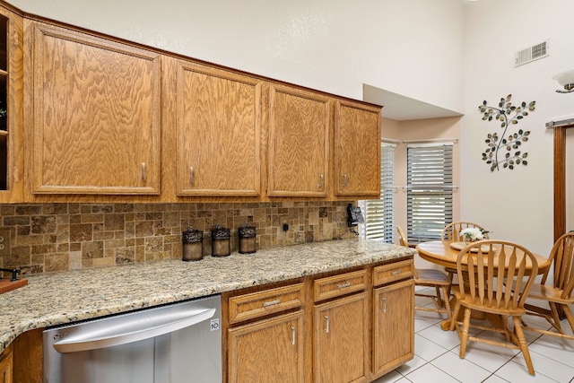 kitchen featuring tasteful backsplash, light stone countertops, dishwasher, and light tile patterned floors