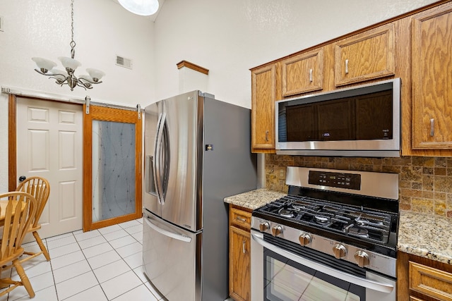 kitchen with decorative backsplash, a towering ceiling, stainless steel appliances, and a chandelier