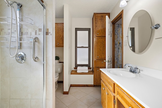 bathroom with tile patterned floors, a textured ceiling, tiled shower, toilet, and vanity