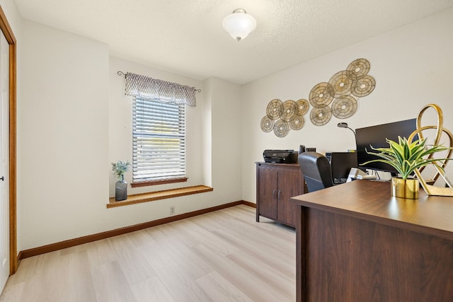 office featuring light wood-type flooring and a textured ceiling