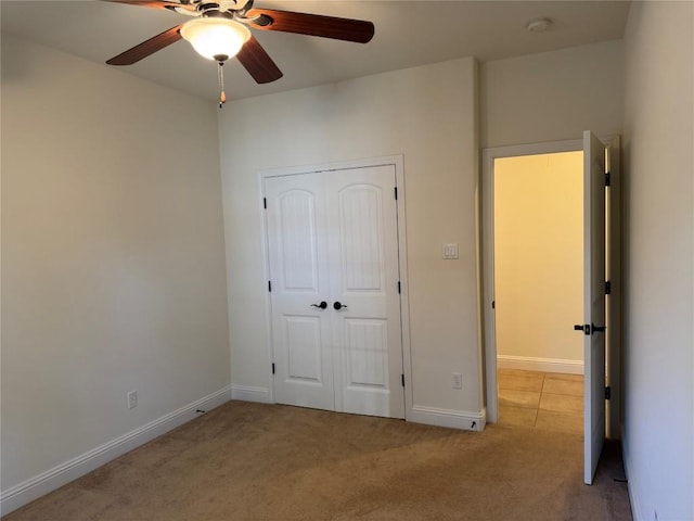 unfurnished bedroom featuring ceiling fan, a closet, and light colored carpet