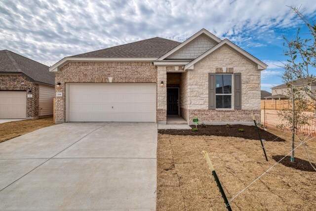 view of front of house featuring roof with shingles, brick siding, fence, a garage, and driveway