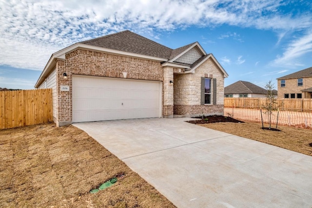 view of front of house featuring concrete driveway, roof with shingles, an attached garage, fence, and brick siding