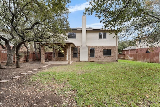 rear view of property with a lawn, a patio area, and solar panels