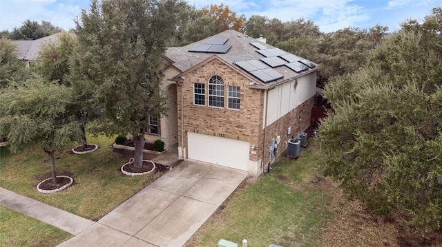 view of front of house featuring central AC unit, solar panels, a garage, and a front lawn