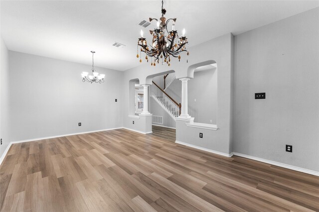 interior space with ornate columns, wood-type flooring, and an inviting chandelier