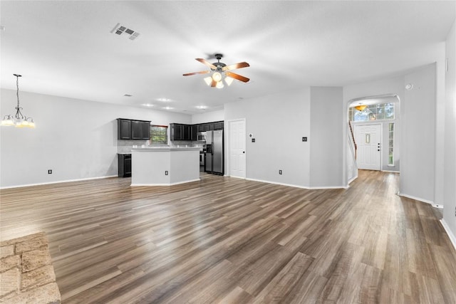 unfurnished living room featuring dark wood-type flooring and ceiling fan with notable chandelier