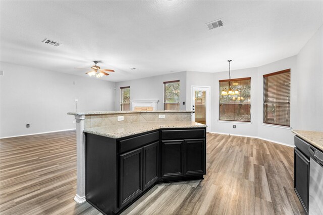 kitchen featuring ceiling fan with notable chandelier, light hardwood / wood-style flooring, a kitchen island, and hanging light fixtures