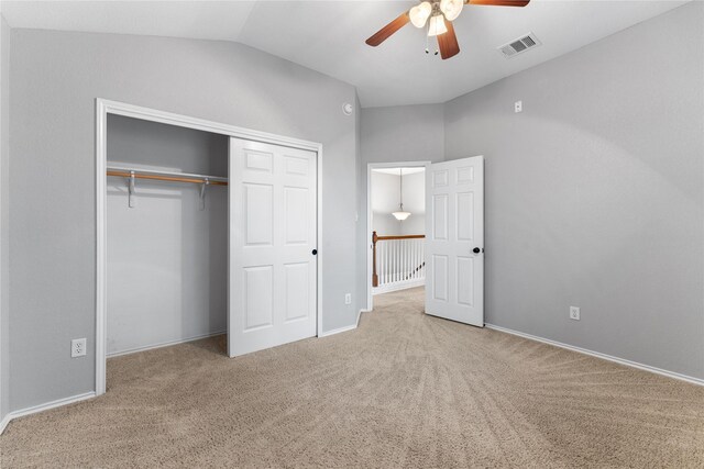 unfurnished bedroom featuring carpet flooring, a closet, vaulted ceiling, and ceiling fan