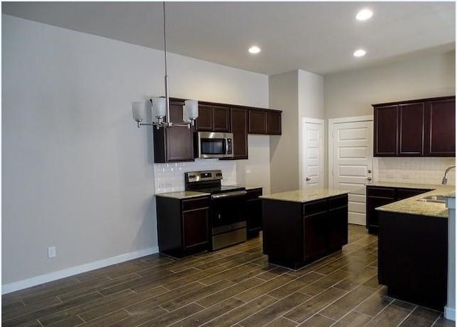 kitchen with sink, a center island, tasteful backsplash, light stone counters, and appliances with stainless steel finishes