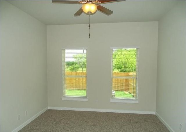 carpeted spare room with ceiling fan