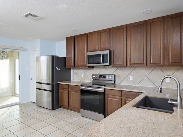 12400 Tay Ter, Austin, TX 78754 - kitchen featuring stainless steel appliances, a sink, tasteful backsplash, light tile patterned floors, and a textured ceiling