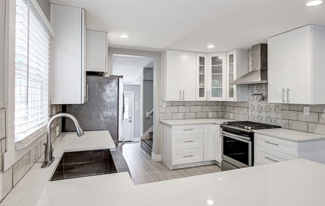 kitchen with sink, white cabinets, wall chimney range hood, and stainless steel range with gas stovetop