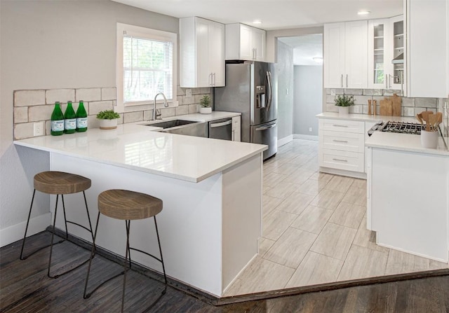 kitchen featuring a breakfast bar, stainless steel appliances, white cabinetry, and sink