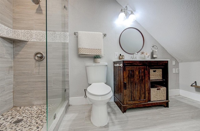 bathroom featuring vanity, toilet, lofted ceiling, and tiled shower