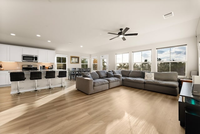 living room with light hardwood / wood-style flooring and ceiling fan