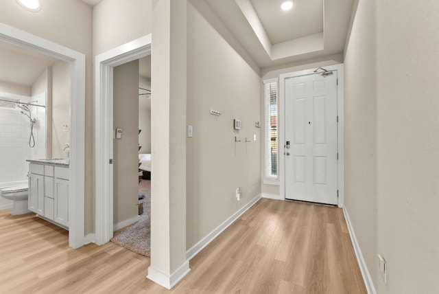 foyer with a tray ceiling and light wood-type flooring