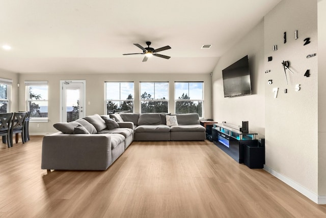 living room featuring ceiling fan, light hardwood / wood-style floors, and vaulted ceiling