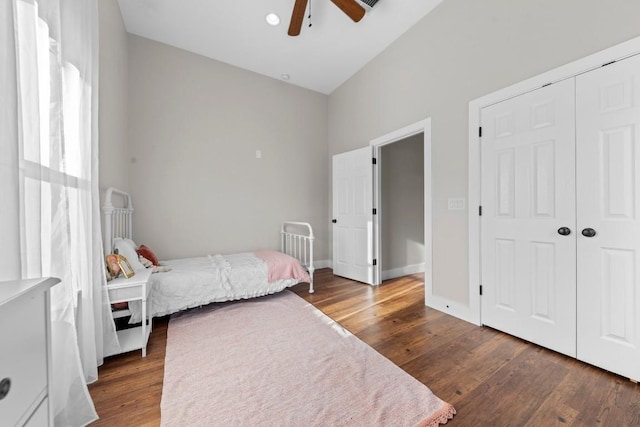 bedroom with ceiling fan, dark hardwood / wood-style floors, lofted ceiling, and a closet